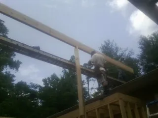 Carpenter setting a ridge beam over a new addition frame — Ice Dam Removal by Roofing Brothers in Warrenton