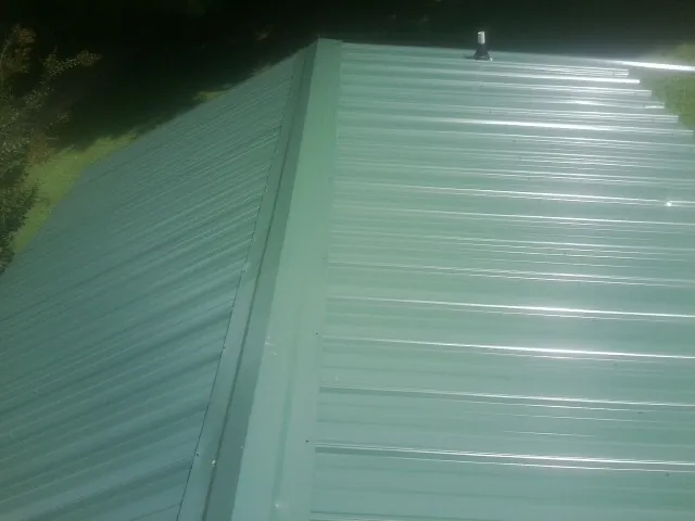 New green metal panels meeting at the ridge of a roof — Flat Roof Repair work by our crew in Warrenton